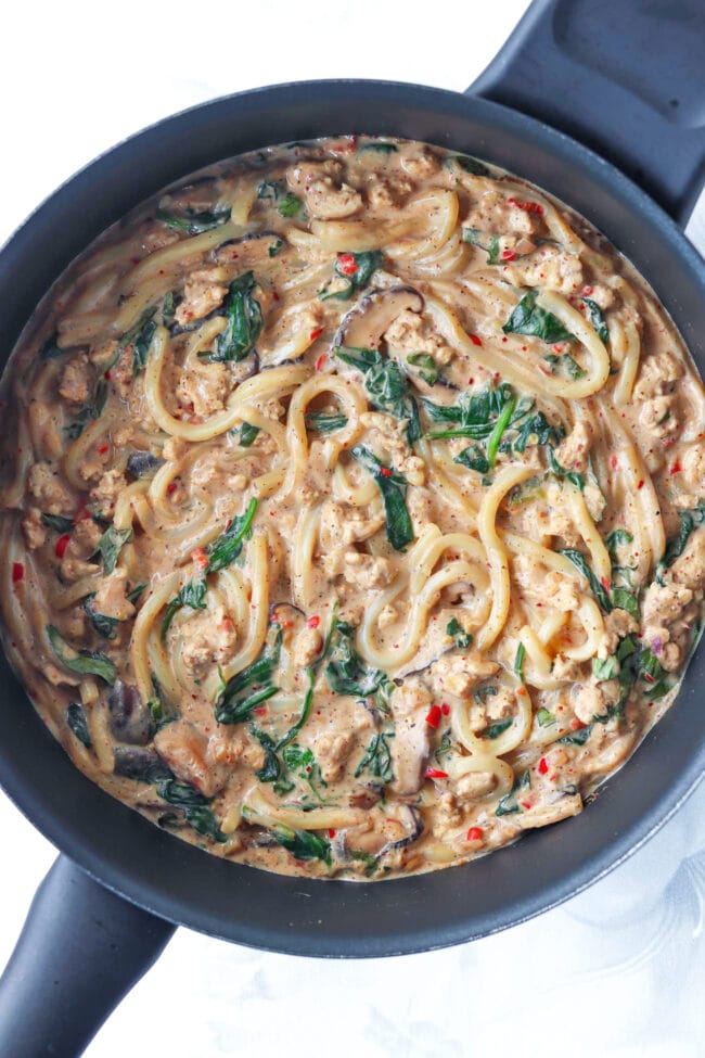 Mushroom udon noodles with ground chicken, mushrooms, spinach and a creamy blended silken tofu sauce in a pan.