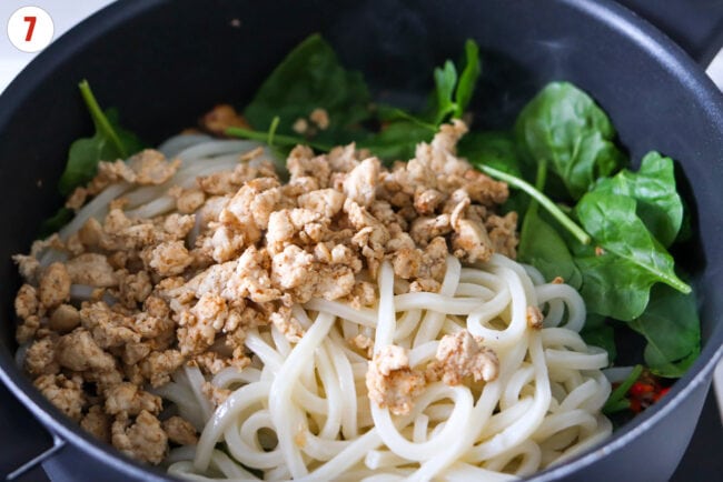 Baby spinach, cooked udon noodles and lean ground chicken in a pan.