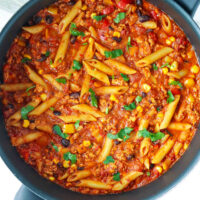 Skillet with high protein chicken taco pasta with cottage cheese topped with chopped cilantro.