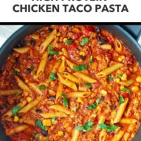 Skillet with chicken taco pasta topped with coriander. Text overlay "Easy Weeknight Dinner!". "High Protein Chicken Taco Pasta" and "That Spicy Chick".