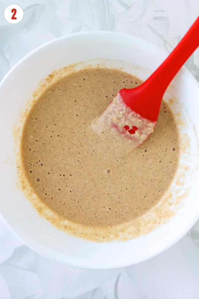 Protein pancake batter in a white bowl with a red silicone spatula.