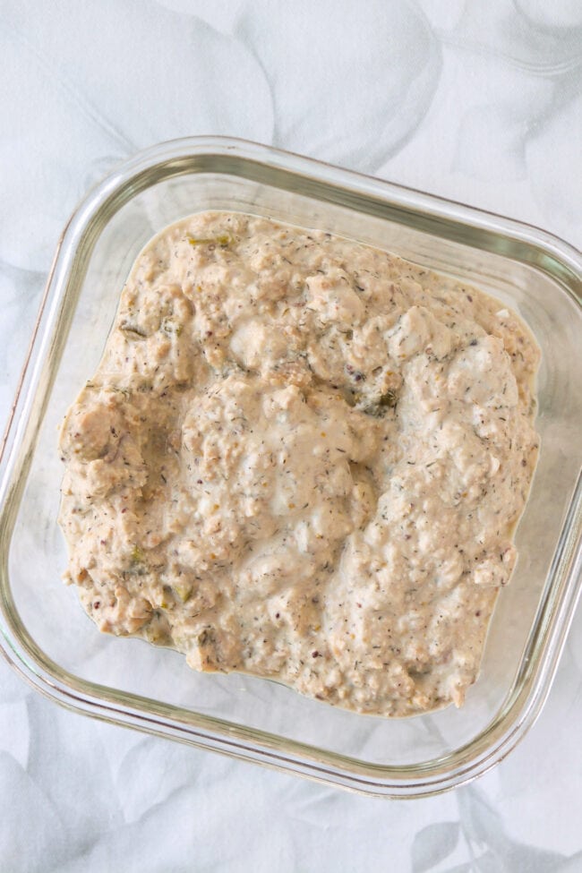 Salmon salad with cottage cheese and dill pickles in a square glass meal prep dish.