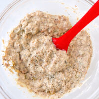 High protein salmon salad with dill pickles in a bowl with a silicone spatula.