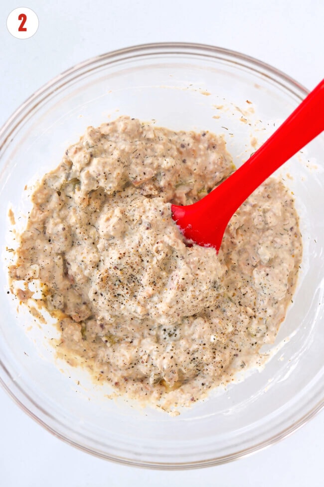 High protein salmon salad with dill pickles in a bowl with a silicone spatula.