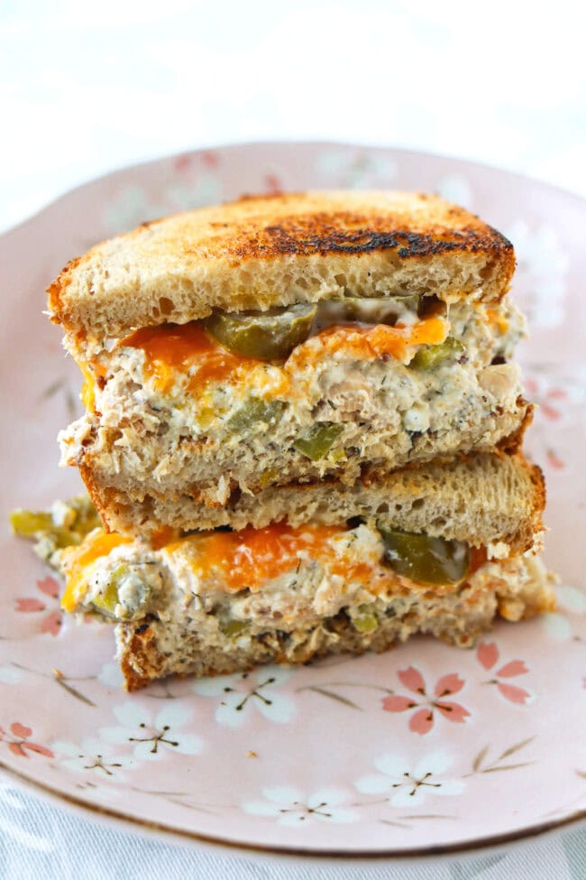 Healthy salmon salad toasted sourdough bread sandwich with cheddar cheese and pickled jalapeños stacked on a plate.