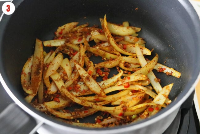 Sautéed sliced onion, garlic, red chilies and curry powder in a pot.
