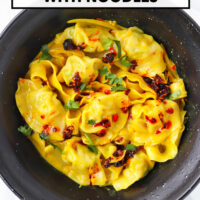 Bowl with curry dumplings with noodles topped with chili crisp and coriander. Text overlay "Curry Dumplings with Noodles" and "That Spicy Chick".