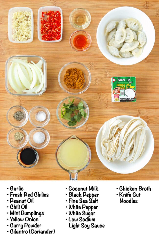 Labeled ingredients for curry dumplings with noodles on a wood board.