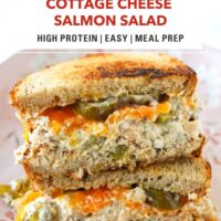 High protein salmon salad sourdough sandwich with cheddar stacked on a light pink plate. Text overlay "Cottage Cheese Salmon Salad", "High Protein | Easy | Meal Prep", and "That Spicy Chick".