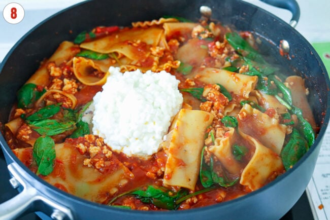 Cottage cheese in pan with spicy vodka sauce lasagna with baby spinach.