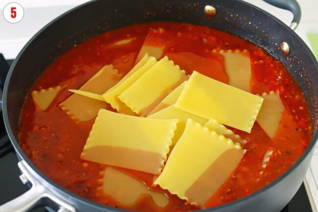 Broken lasagna noodles in a skillet with spicy vodka sauce.