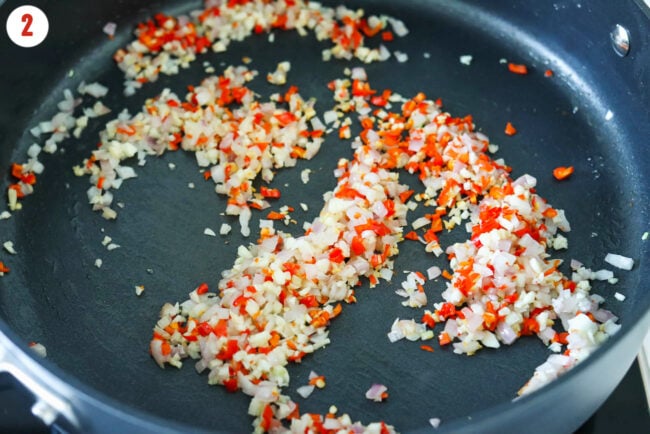 Sautéed shallots, garlic, and chilies in a skillet.