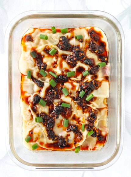 Top view of dish with dumpling lasagna topped with chili crisp and spring onion.