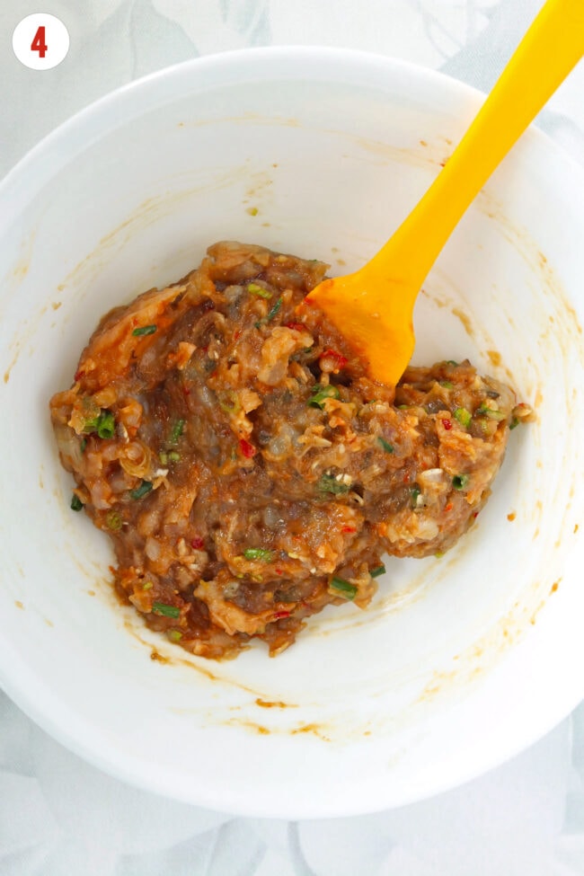 Chicken and shrimp filling mixture for dumpling lasagna in a bowl with a yellow silicone spatula.