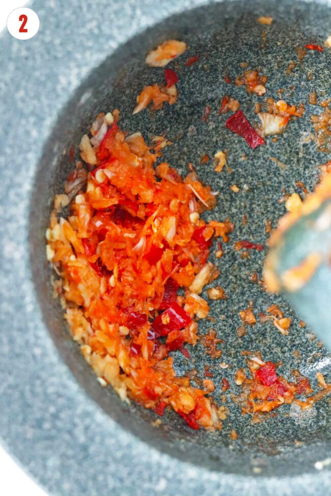 Smashed garlic, chili, and ginger in a mortar.