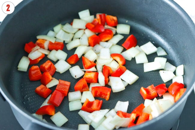 Sautéed diced onion and red bell pepper in a skillet.