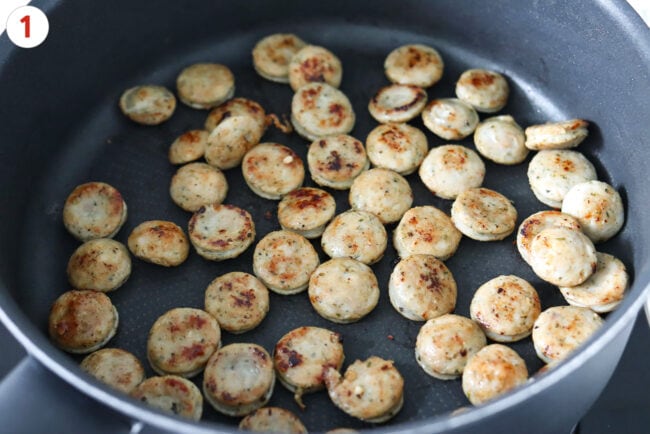 Seared chicken sausage coins in a skillet.