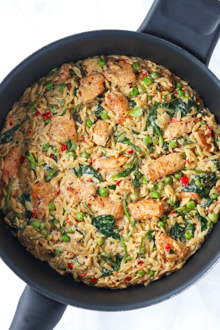 Closeup of Creamy Lemon Chicken Orzo garnished with sliced basil in a deep-edged skillet.