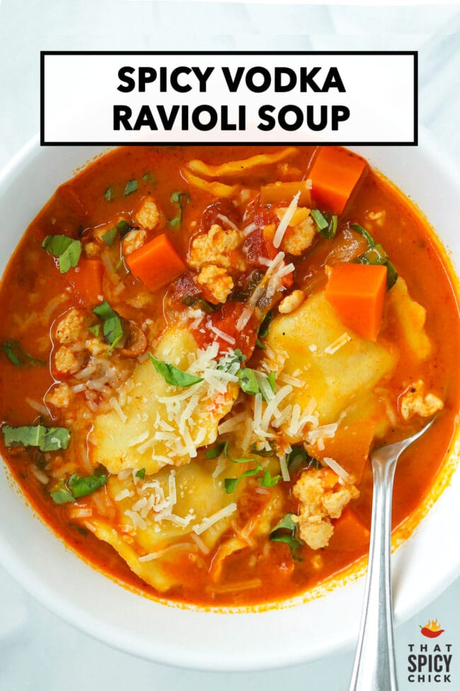 Spicy ravioli soup with ground chicken topped with grated parmesan and sliced basil in a bowl with a spoon. Text overlay "Spicy Vodka Ravioli Soup" and "That Spicy Chick".