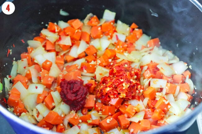 Double concentrated tomato paste and Calabrian chili paste in pot with sautéed carrots, onion, garlic and red chilies.
