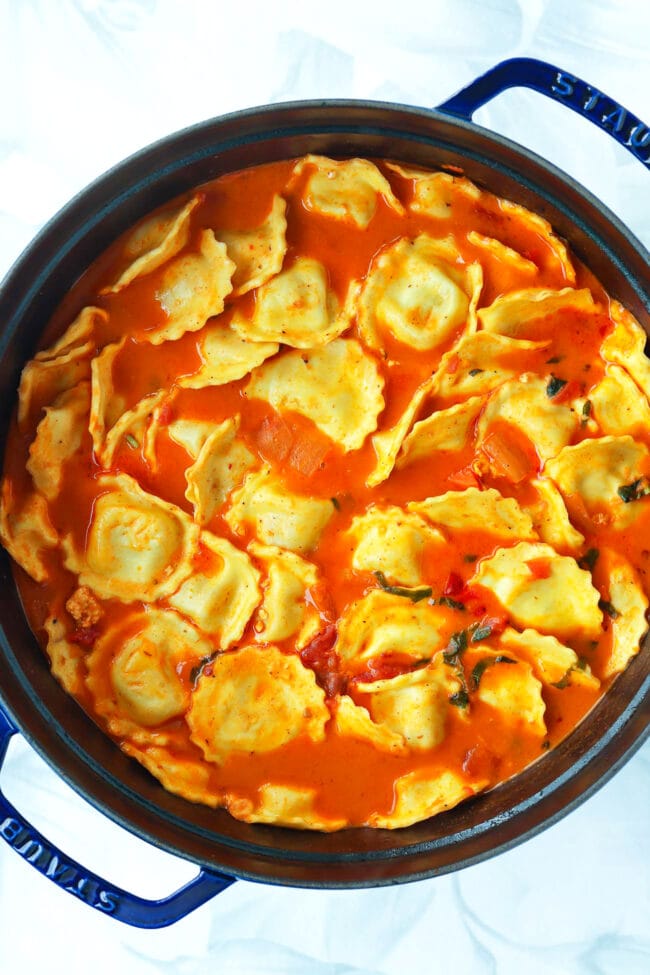 Large blue Dutch oven with spicy vodka ravioli soup.