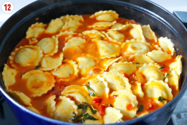 Ravioli cooking in a large pot with spicy vodka soup.
