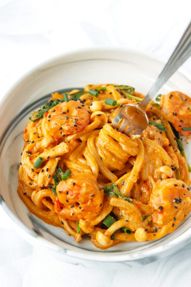 Udon noodles twirled around fork in a plate with Creamy Buldak Sauce Udon.