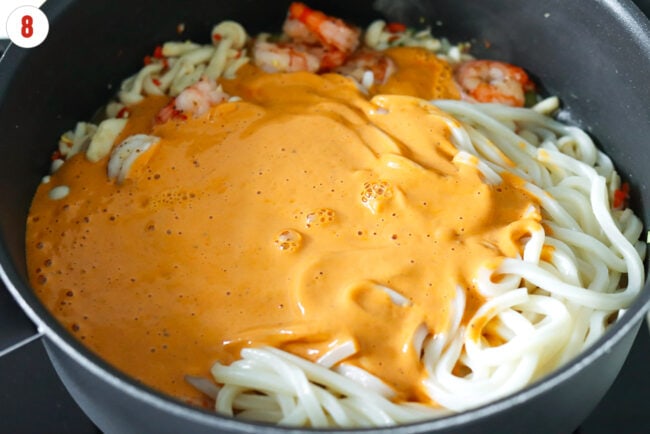 Creamy buldak tofu sauce in on udon noodles in a pan.