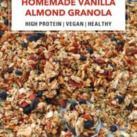 Vanilla almond granola on a baking tray with a spoon. Text overlay "Homemade Vanilla Almond Granola", "High Protein | Vegan | Healthy" and "That Spicy Chick".