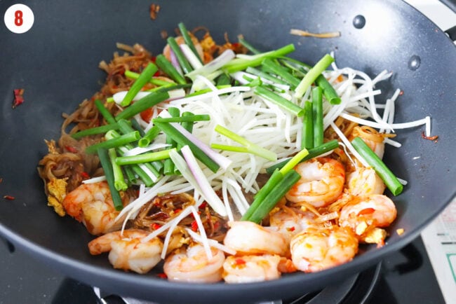 Bean sprouts and spring onion added to wok with shrimp and rice noodles stir-fry.