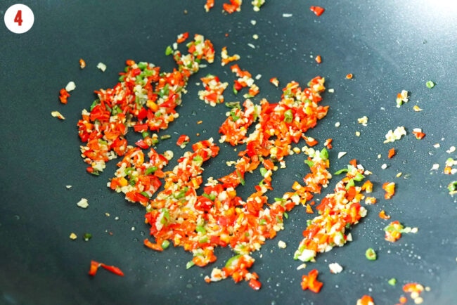 Stir-fried garlic, red chilies and green chilies in a wok.
