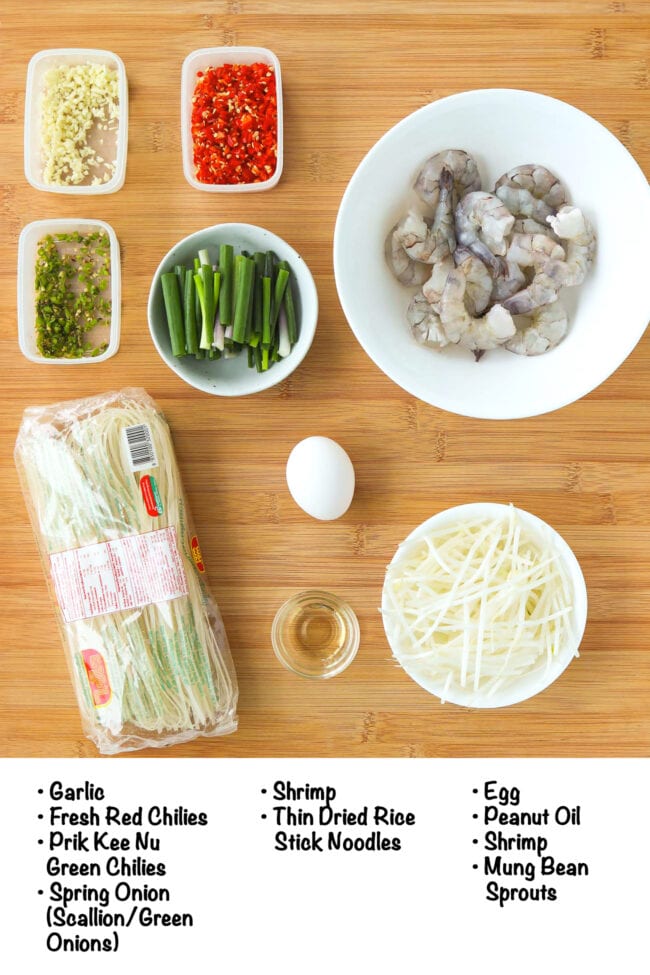 Labeled fresh and pantry ingredients for Pad Mee Korat with Shrimp on a wood board.