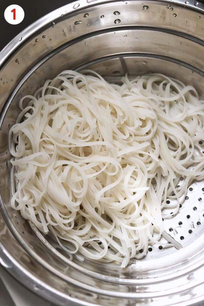 Soaked and drained thin dried rice noodles in a colander.