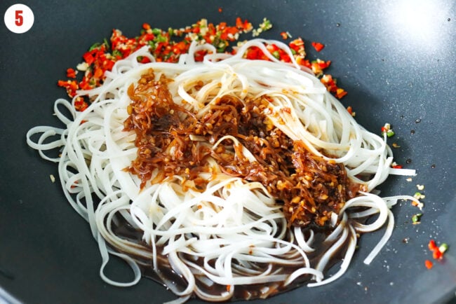 Added pad me korat sauce and soaked rice noodles to wok with stir-fried garlic and chilies.