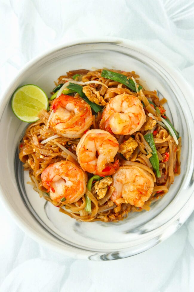 Pad Mee Korat with Shrimp on a marble plate with a slice of lime on the side.