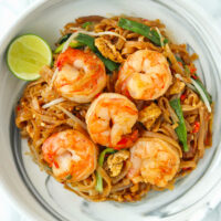 Closeup of Pad Mee Korat with Shrimp on a marble plate with a lime cheek on the side.