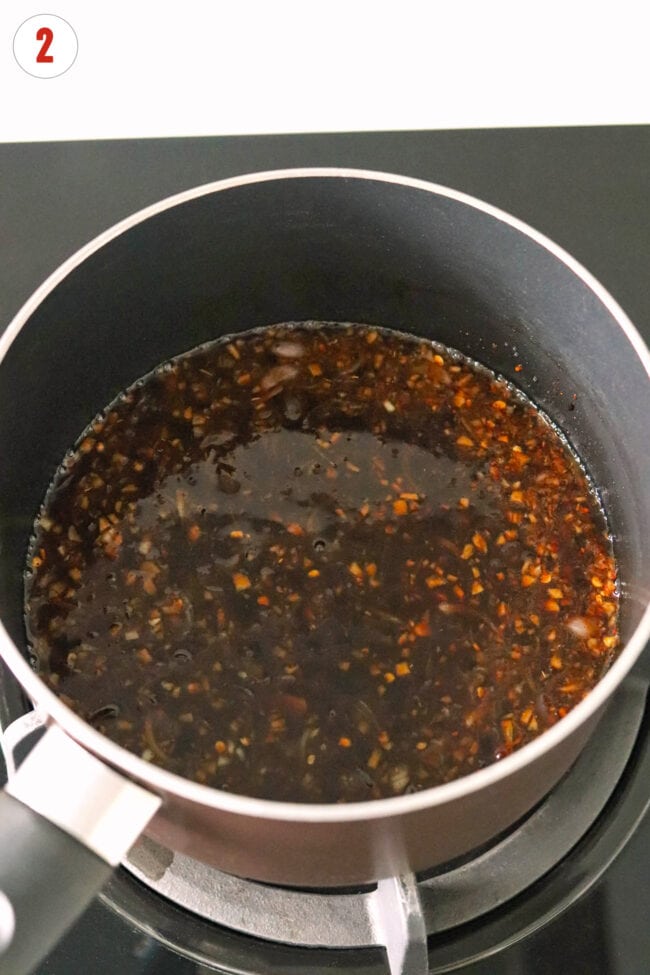 Simmering pad mee korat sauce in a pot on the stovetop.
