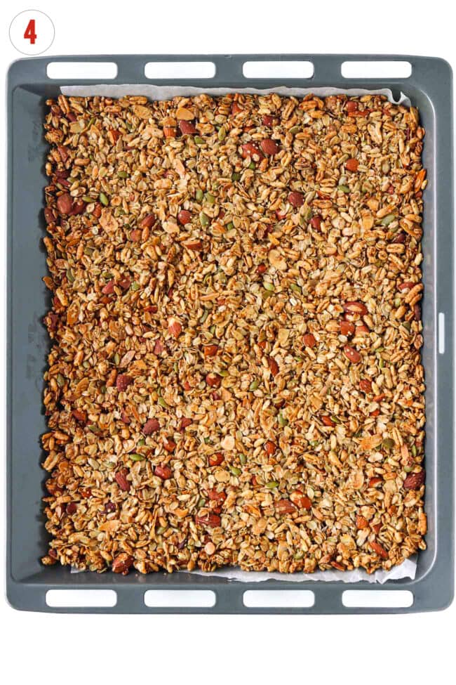Baked vanilla almond granola on a sheet pan lined with parchment paper.