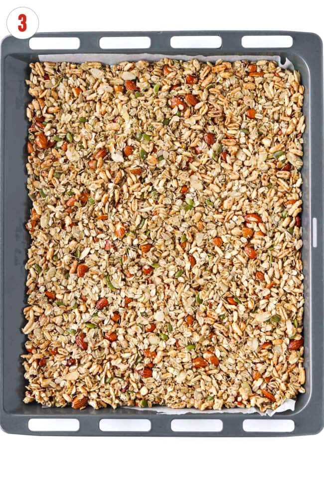 Unbaked vanilla almond granola on a sheet pan lined with parchment paper.