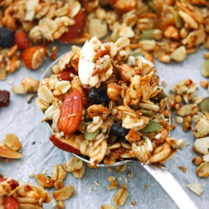 Closeup of spoon with vanilla almond granola with dried blueberries.