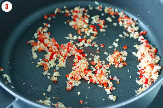 Sautéed shallots, garlic, and red chilies in a pan.