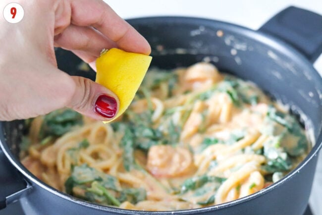 Squeezing lemon juice into pan with white bean miso sauce udon noodles with shrimp.