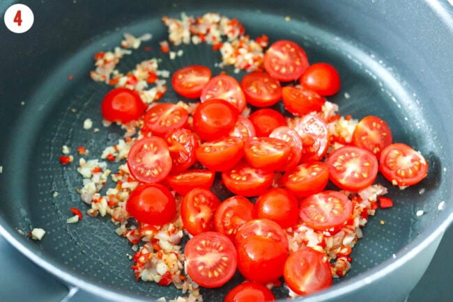 Halved cherry tomatoes added to pan with sautéed shallots, garlic and red chilies.