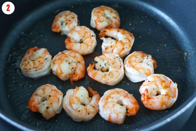 Sautéed jumbo shrimp seasoned with black pepper and salt in a pan.