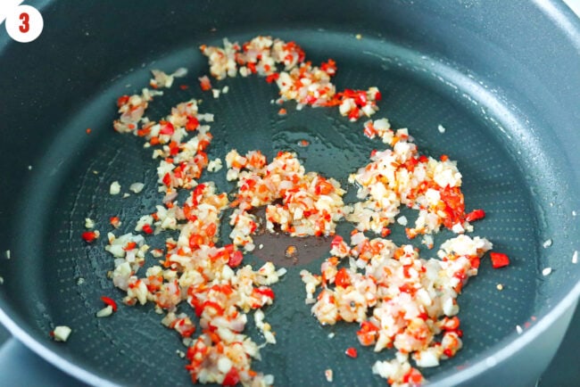 Sautéed garlic, red chilies and shallots in a skillet.