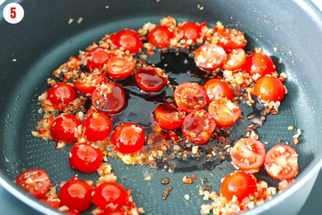 Oyster sauce and soy sauce in pan with cherry tomatoes and sauteed garlic, shallots, and red chilies.