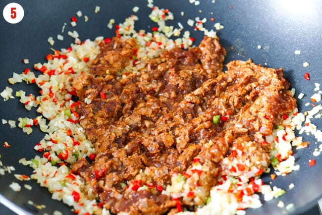 Cooking Korean ground chicken in a wok with sautéed onion, garlic and chilies.