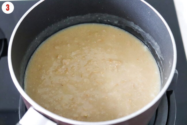 Creamy savory oatmeal with egg whites cooked in bone broth in a pot.
