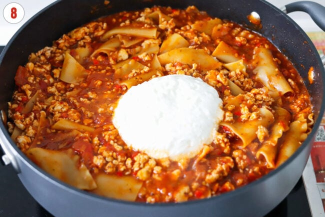 Cottage cheese in pan with spicy red pesto chicken lasagna.