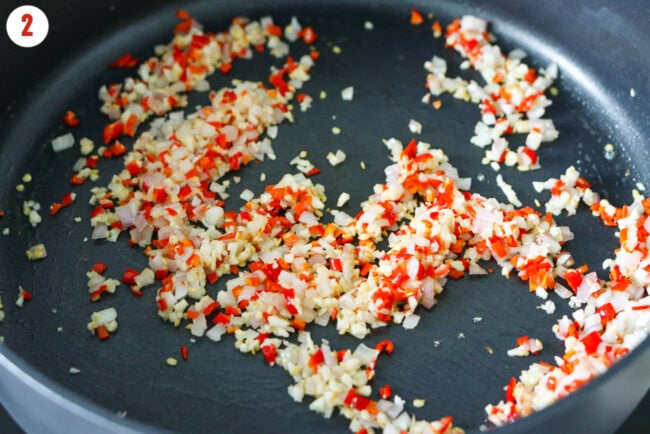 Sautéed garlic, shallots and fresh red chilies in a skillet.